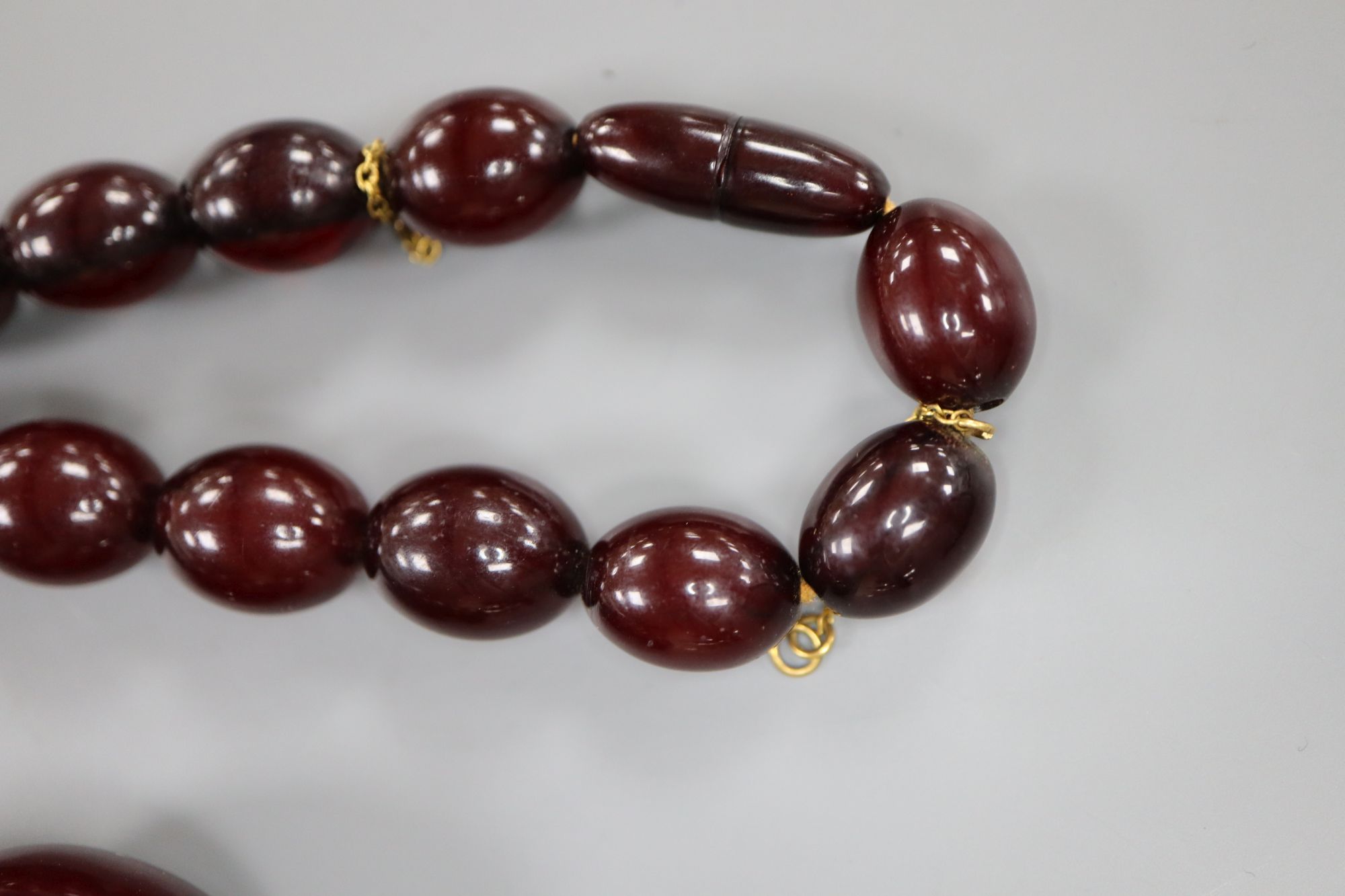 A single strand graduated simulated cherry amber oval bead necklace, 61cm, gross weight 99 grams.